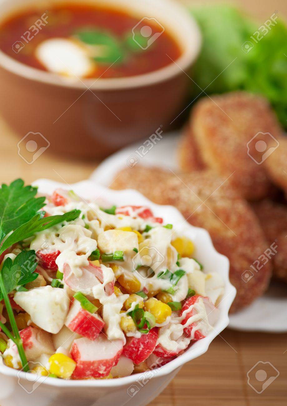 11254740-delicious-dinner-closeup-bowl-crab-salad-burgers-borscht-background-wooden-table-Stock-Photo.jpg