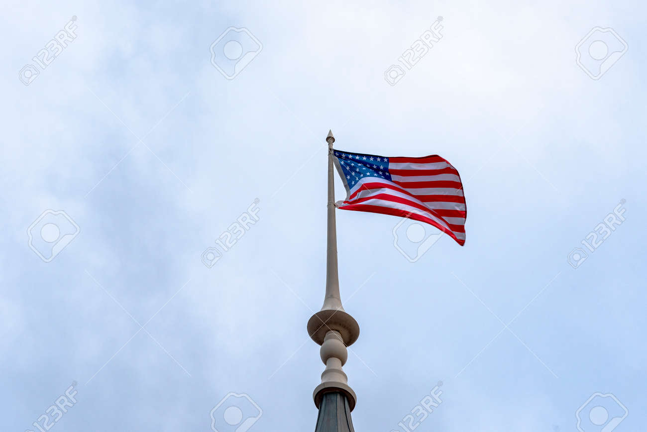 American flag waving in blue sky. American flag at the top. - 159417904 American flag waving in blue sky. American flag at the top. - 159417904