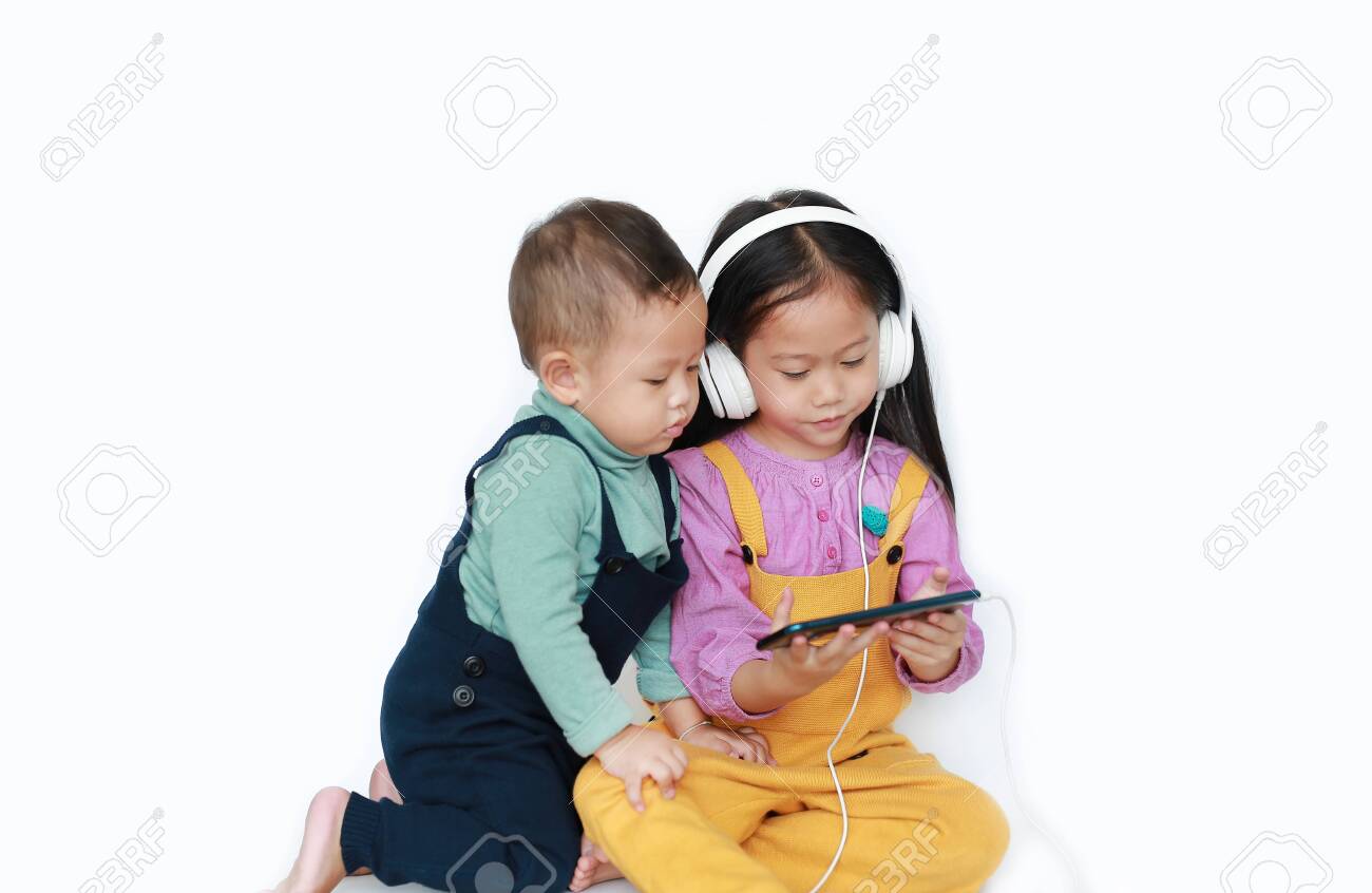 Adorable Asian older sister and little brother sharing to enjoys listening music with headphones by smartphone isolated over white background. Sharing concept. - 126559313 Adorable Asian older sister and little brother sharing to enjoys listening music with headphones by smartphone isolated over white background. Sharing concept. - 126559313