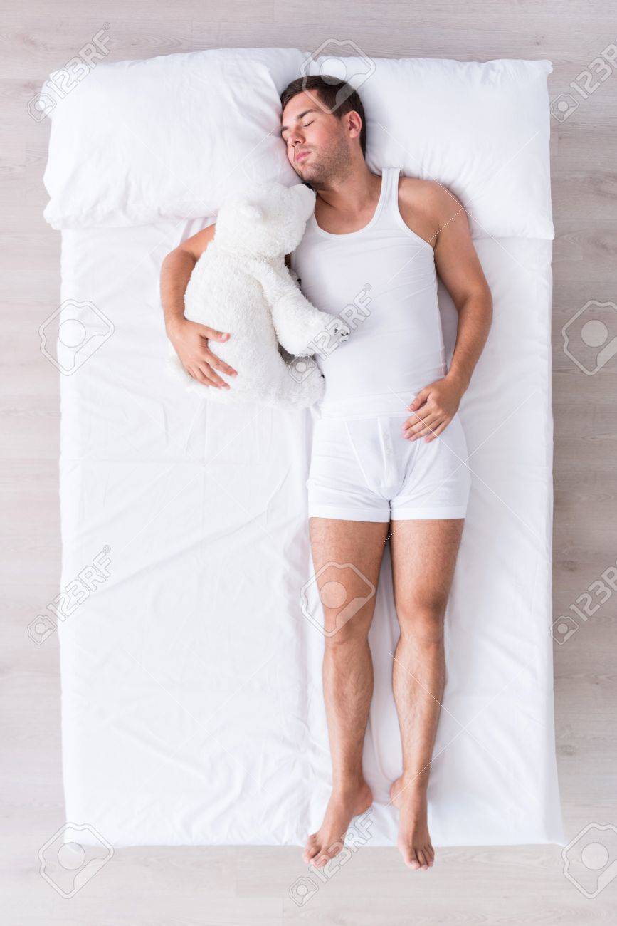 Comme Un Bebe Vue De Dessus Du Jeune Homme Decontracte Qui Dort Sur Le Dos Sur Un Grand Lit Blanc Portant Des Sous Vetements Blancs Tout En Etreignant Son Ours En Peluche Banque