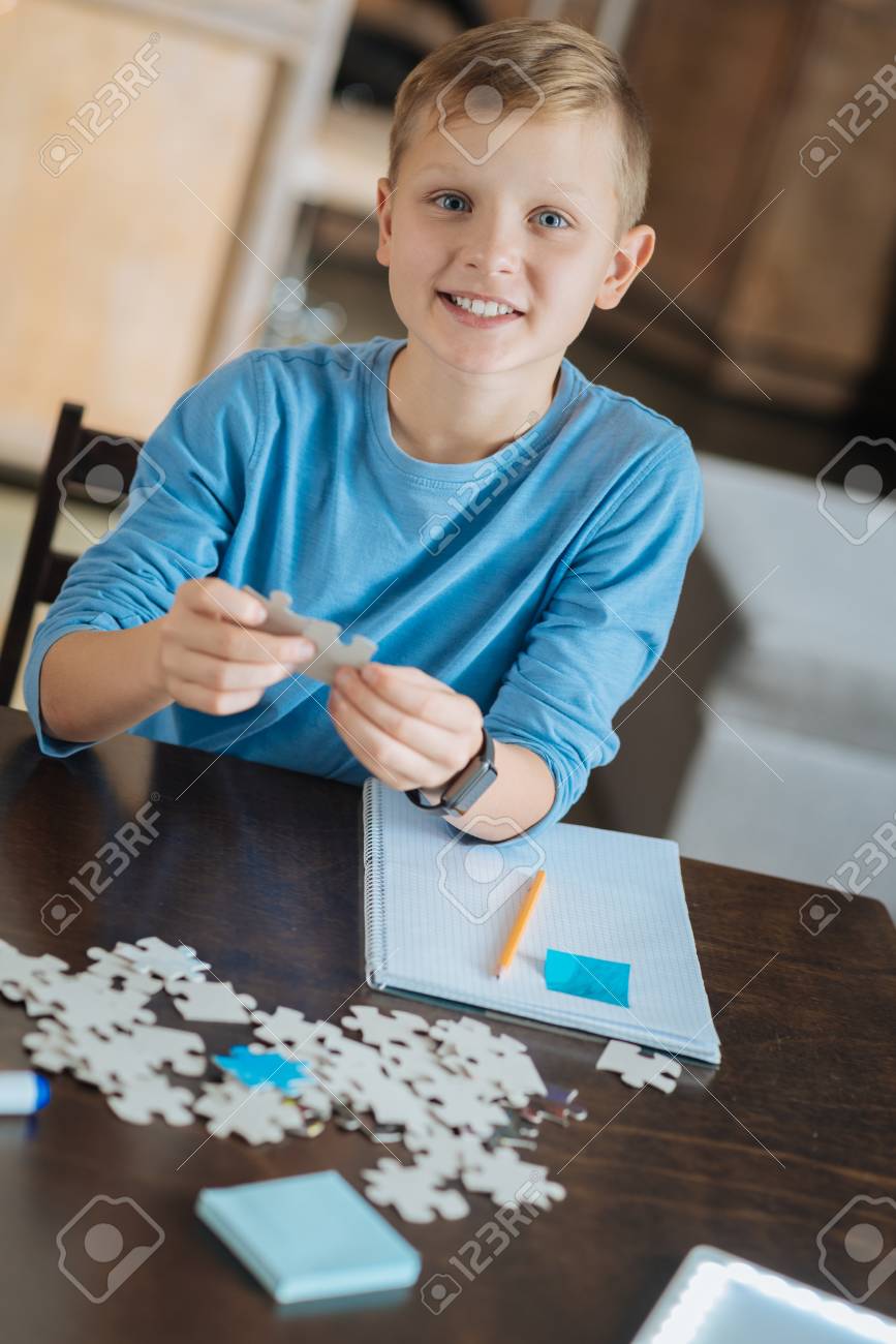 面白いエンターテイメント スマート楽しいすてきな男の子一緒にジグソー パズルのピースを置くと テーブルに座って彼らを見て の写真素材 画像素材 Image