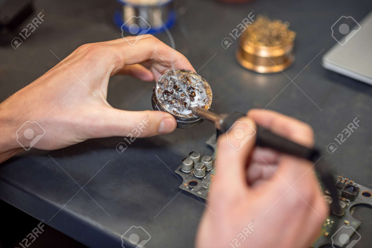 Hands with hot soldering iron touching solder - 167899943 Hands with hot soldering iron touching solder - 167899943