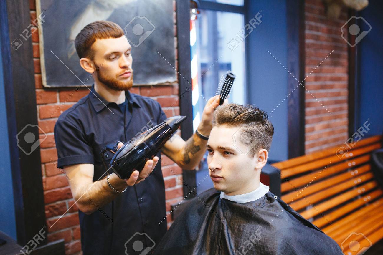 Male Barber Makes Hair Styling Using A Dryer Of A Young Man