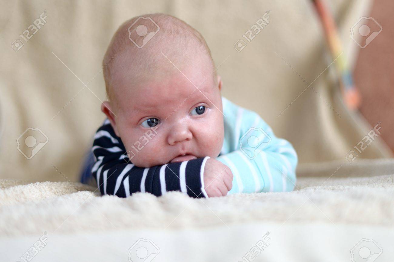 Cute 1 5 Month Old Caucasian Baby Boy With Short Blonde Hair Wearing A Bright Cloth And Lying On His Front On A Bed Stock Photo Picture And Royalty Free Image Image