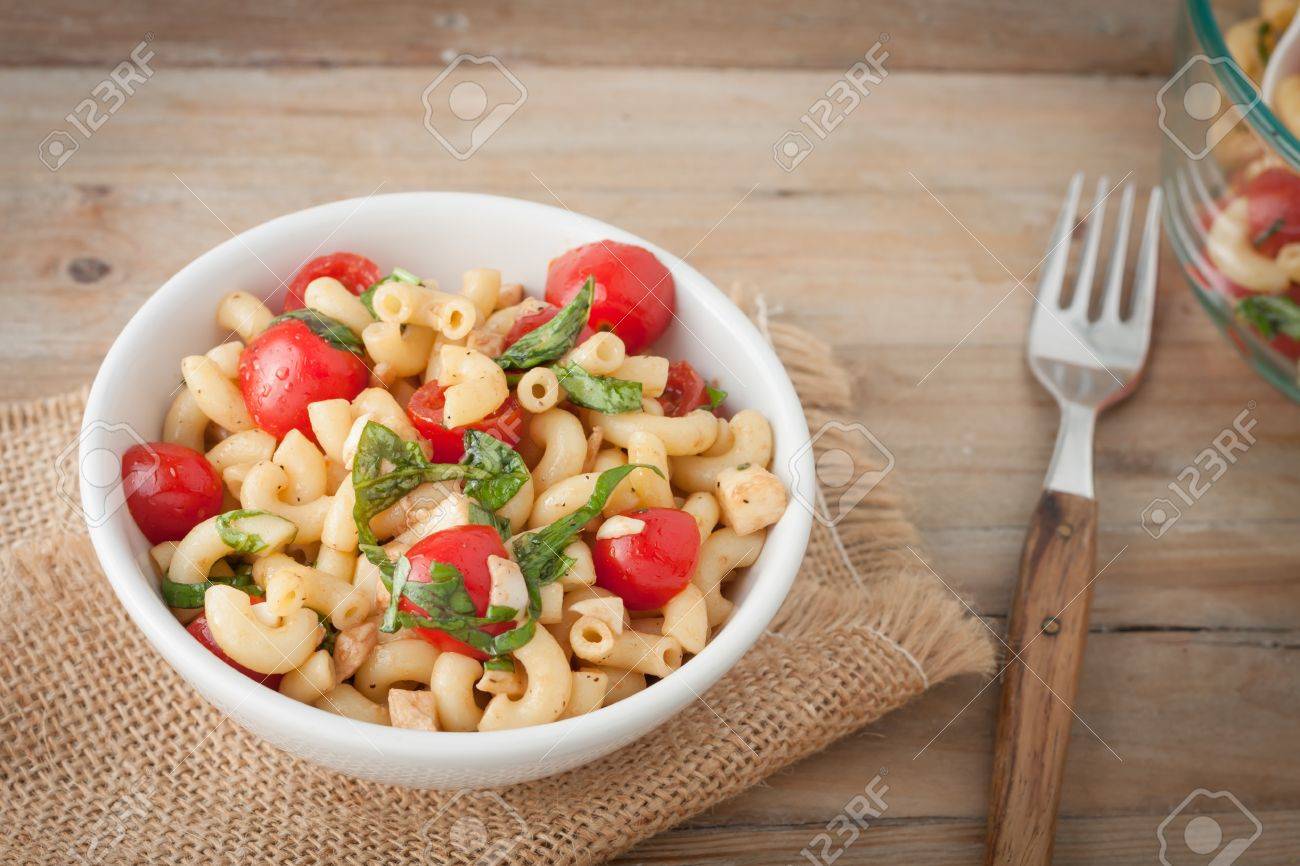 Italian macaroni salad with tomatoes and fresh basil in white bowl over wooden background - 41918046 Italian macaroni salad with tomatoes and fresh basil in white bowl over wooden background - 41918046