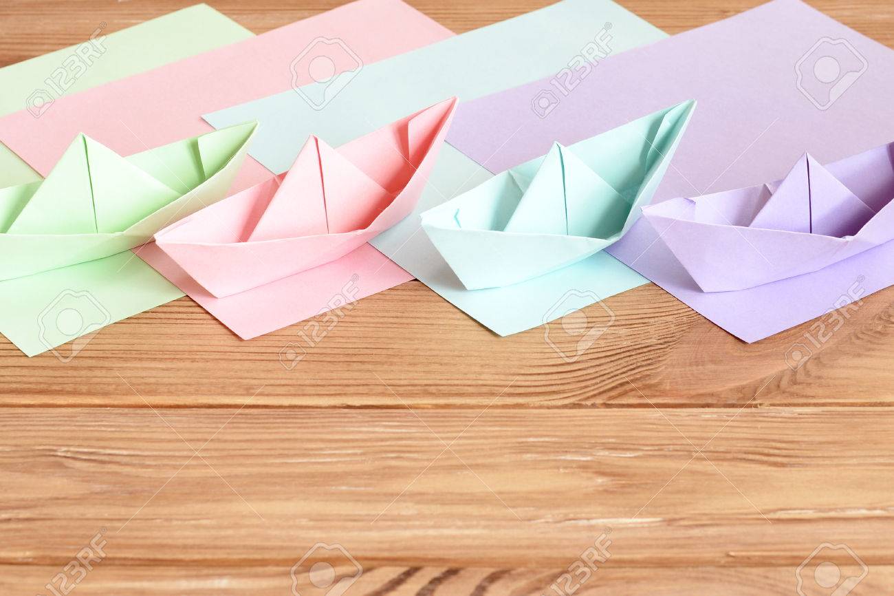 ピンク グリーン ライラック 青い折り紙船本文空スペースの木製のテーブルの上のおもちゃ 色付きの紙シート 子供のための簡単夏の折り紙 子供のための手工芸 の写真素材 画像素材 Image