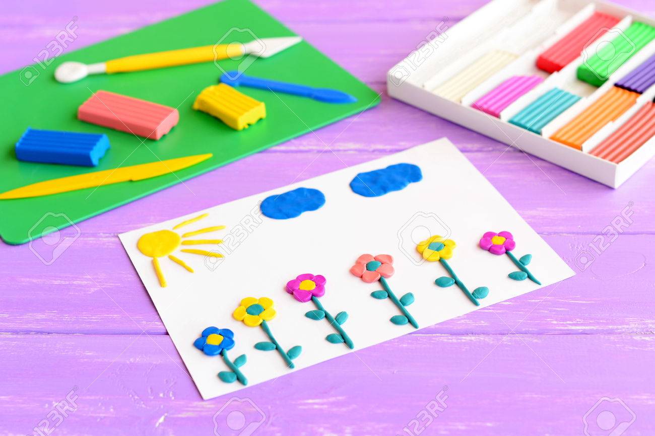 Tarjeta Con Flores De Plastilina, El Sol Y Las Nubes. Plastilina Sobre Una Mesa De Madera. Los Niños De Modelado De Arcilla Arte. Idea De Manualidades Para El Desarrollo De La Motricidad Tarjeta Con Flores De Plastilina, El Sol Y Las Nubes. Plastilina Sobre Una Mesa De Madera. Los Niños De Modelado De Arcilla Arte. Idea De Manualidades Para El Desarrollo De La Motricidad