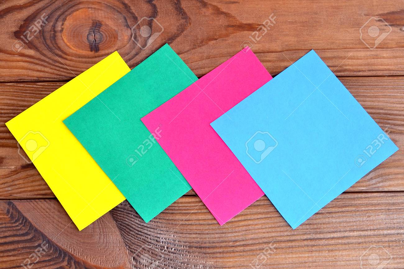 multicolored paper square sheets on a wooden table paper set