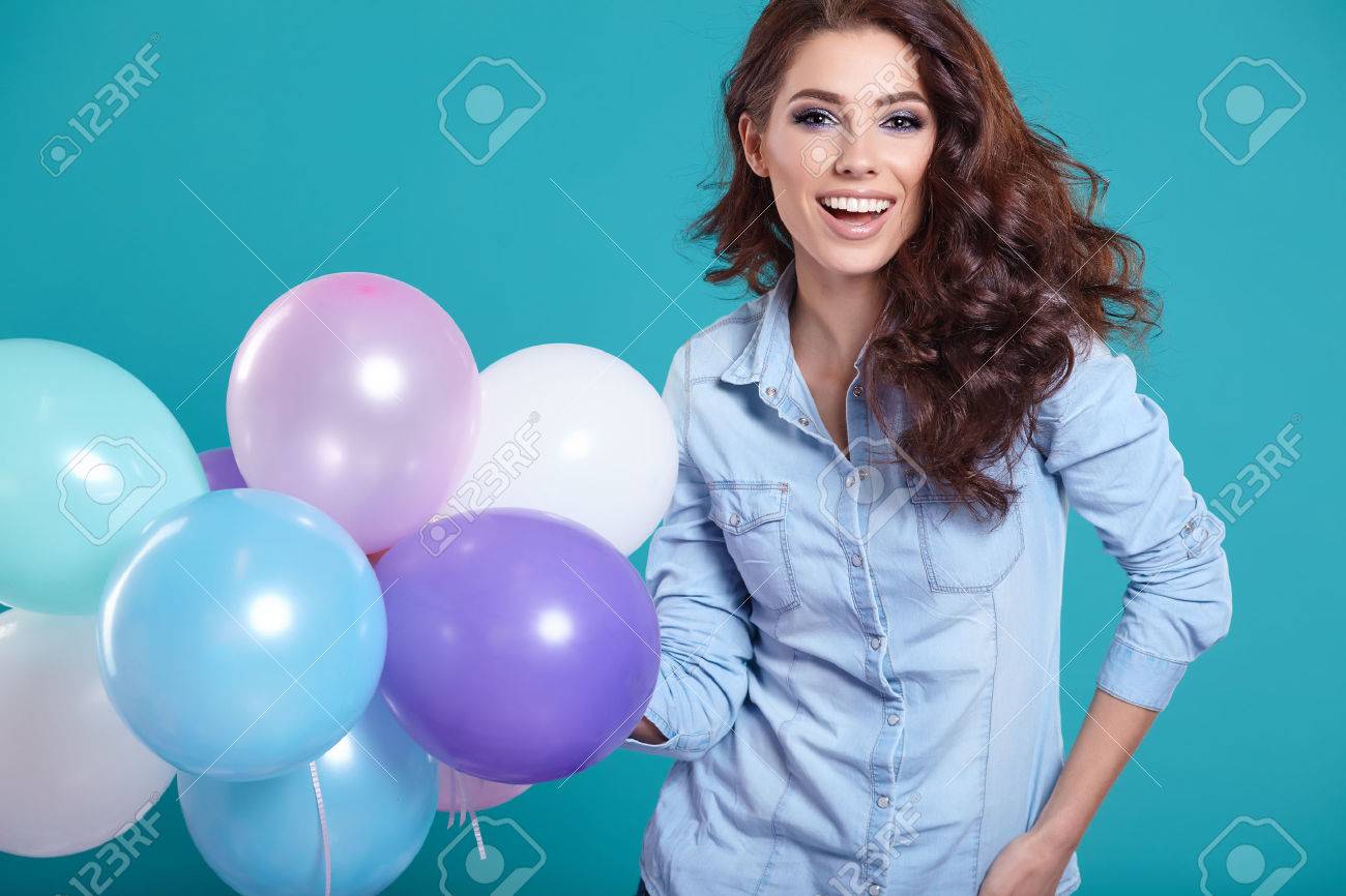 Happy young woman standing over blue wall and holding balloons. Pleasure. Dreams. Toned. - 51924426 Happy young woman standing over blue wall and holding balloons. Pleasure. Dreams. Toned. - 51924426