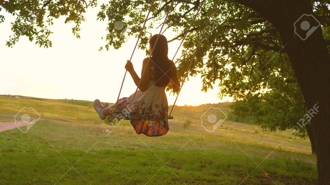 Beautiful Girl In A Dress In A Park On A Swing Flies Young Girl Stock Photo Picture And Royalty Free Image Image